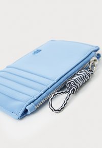 Carte de vizită de culoare albastru deschis, fabricată dintr-un material neted, având multiple sloturi pentru carduri, un compartiment cu fermoar și o buclă pentru breloc cu dungi.