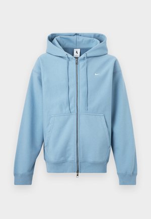 Jasnoniebieska bluza z kapturem na zamek, z przednimi kieszeniami, kapturem ze sznurkiem i małym białym logo Nike na piersi.