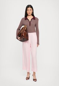 Smeđa long-sleeve rebrasta majica s tamnocrvenim ovratnikom, svijetloružičaste široke hlače, smeđa kožna torba s lancem, smeđe cipele s petom.