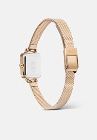 Goldener Edelstahl-Mesh-Uhr mit rechteckigem weißen Zifferblatt. Verfügt über einen Klappverschluss und ein graviertes Logo am Armband. Minimalistisches Design.