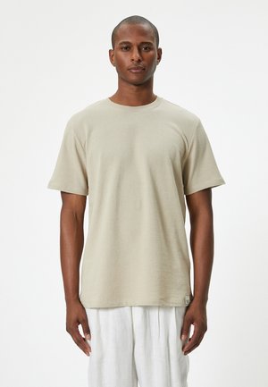 Beige T-shirt met korte mouwen van zachte stof, met een ronde hals, een relaxte pasvorm en subtiele textuurdetails. Label aan de onderkant.