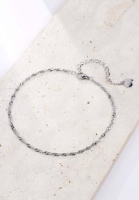 Collar de cadena torcida de plata con un cierre y longitud ajustable. Presenta un pequeño detalle en forma de corazón. Textura metálica suave.