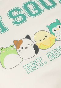 Il tessuto bianco presenta un design con quattro animali dei cartoni animati: una rana verde, un gatto calico, un pulcino giallo e un gufo turchese, con il testo "SQUAD EST. 2018".