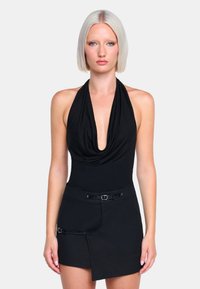 Schwarzer Halter-Bodysuit mit tiefem Ausschnitt, kombiniert mit einem Minirock aus strukturiertem Stoff und einem Gürtelakzent mit Vorderverriegelung.
