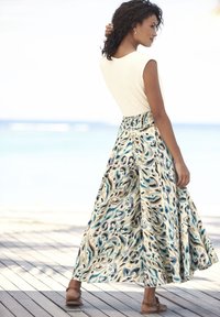 Maxikleid mit einem cremefarbenen, eng anliegenden Oberteil und fließendem Rock im blauen, beigen und braunen abstrakten Muster. Leichtes Material; knöchellanges Design.