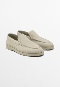 Mocassins en cuir beige à enfiler avec un dessus texturé, un bout mocassins cousu et une semelle épaisse, positionnés côte à côte sur un fond blanc.