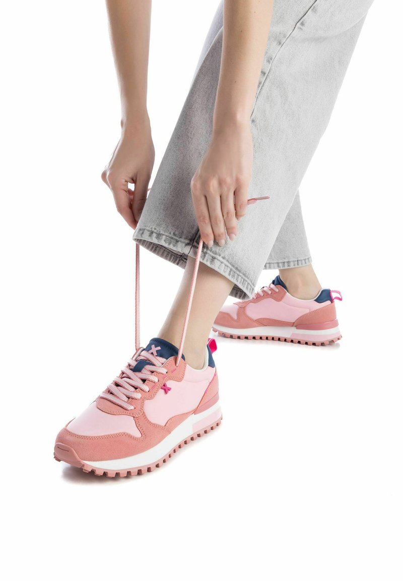 Zapatillas deportivas rosas con un diseño de materiales mixtos, que presentan ante y malla, suela blanca, acentos azules y cordones en contraste.