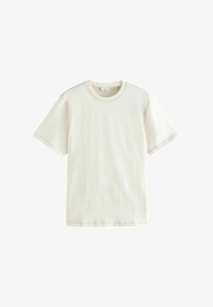 T-shirt di cotone in avorio con maniche corte, scollo rotondo e dettaglio di cuciture a contrasto. Tessuto leggero con una texture liscia.