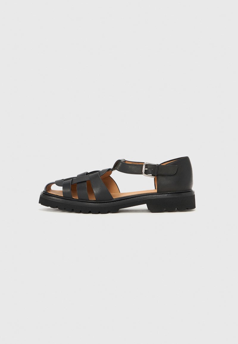 Sandales en cuir noir avec plusieurs sangles, design ouvert à l'avant, boucle à la cheville et semelle texturée pour l'adhérence.