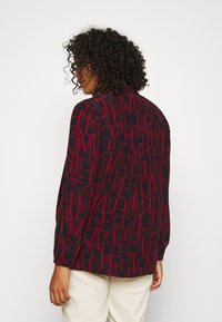 Langaarm shirt in donker marineblauw met gedurfde, abstracte rode lettering. Heeft een relaxte pasvorm, knopmansjetten en een gebogen zoom. Gemaakt van een katoenmix.