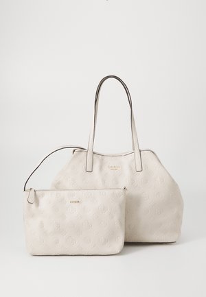 Set di borse in pelle beige include una borsa più grande con spallacci e una pochette con zip più piccola. Entrambi presentano motivi a logo impresso.
