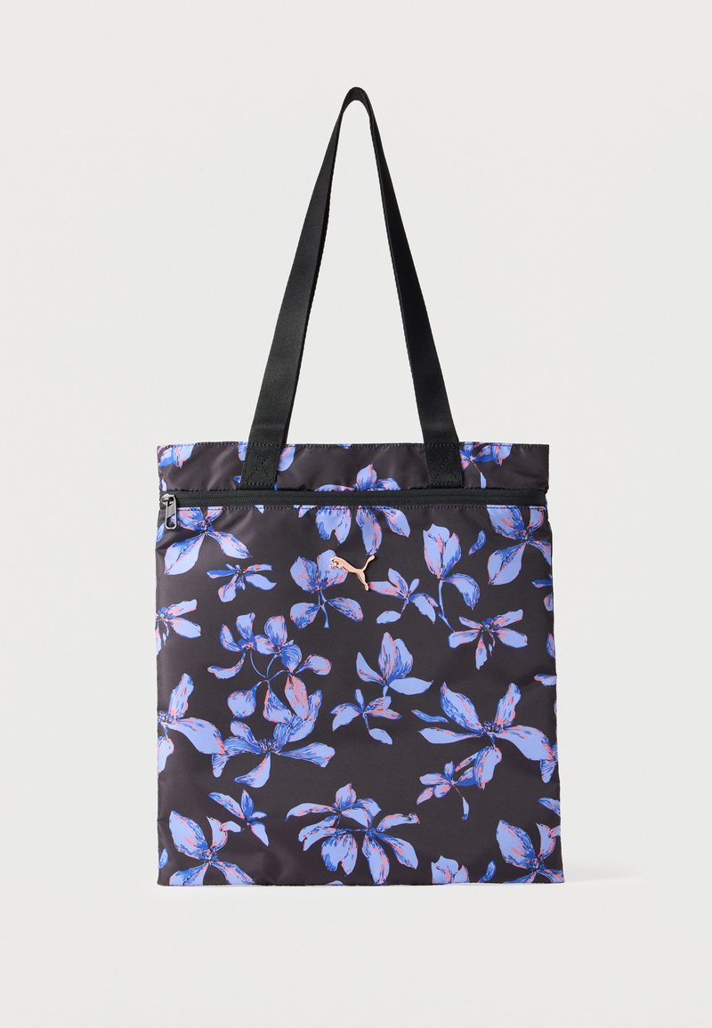 Sac fourre-tout noir avec motif floral bleu et rose, poignées noires, poche zippée à l'avant, et petit logo Puma métallique sur le devant.