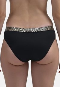 Fekete bikini alsó, arany mintázattal ellátott textúrált derékpánttal. Közepes magasságú szabás és sima anyag a kényelem érdekében.