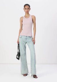 Lys rosa tettsittende tanktop, lyseblå brede ben jeans, svarte stroppehæler og en liten svart håndveske. Glatt stoff og uformelt design.