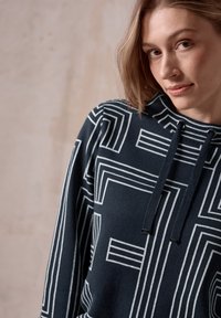 Marineblauer Hoodie aus weichem Stoff, mit einem weißen geometrischen Muster, verstellbaren Kordeln und einer lässigen Passform.