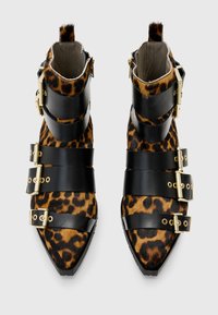 Bocanci scurți cu imprimeu de leopard, având curele din piele neagră cu catarame aurii, design cu vârful ascuțit și accente de blană texturată.