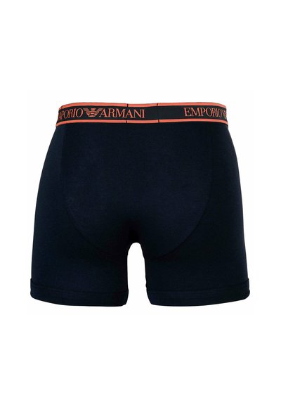 Schwarze Boxershorts mit orangefarbenem Emporio Armani gebrandetem Bund, von hinten gezeigt, vor einem schlichten weißen Hintergrund.