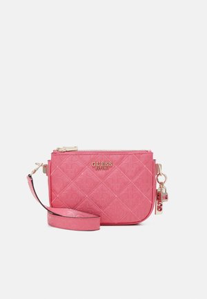 Pink quilted Guess crossbody bag with gold logo, zip closure, adjustable strap, and decorative gold-tone charm on a white background.