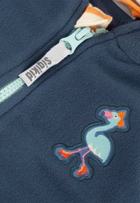 Marineblaue Fleecejacke mit einem türkisfarbenen Reißverschluss und einem verspielten, gestickten Flamingo-Motiv mit orangefarbenen Rollschuhen und einer Schleife.