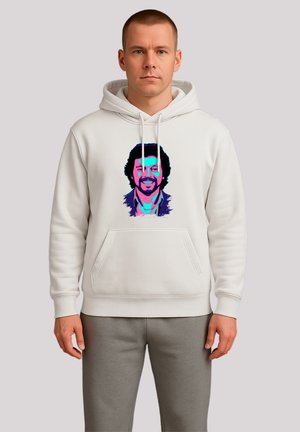 Mann, der einen weißen Hoodie trägt, auf dem ein farbenfrohes Pop-Art-Porträt eines lächelnden Mannes mit lockigem Haar auf der Vorderseite zu sehen ist.