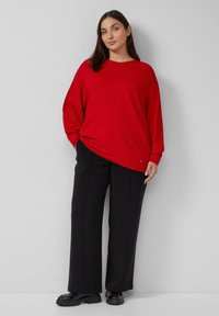 Rode geribde longsleeve top gecombineerd met high-waisted zwarte wijde broek en chunky zwarte schoenen. Minimalistisch ontwerp, relaxte pasvorm.