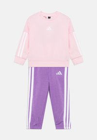 Pink sweatshirt with white stripes on sleeves and logo; paired with purple pants featuring white side stripes and logo. Soft fabric, sporty design.
