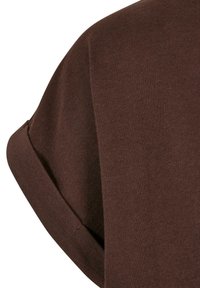 Dunkelbraunes Kurzarmhemd mit ordentlich umgeschlagenem Ärmel, das die Stoffstruktur und die Steppdetails zeigt.