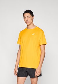 Κίτρινη αθλητική μπλούζα από ελαφρύ, διαπνέον ύφασμα με κοντά μανίκια. Διαθέτει μικρό λογότυπο στο στήθος και κλασική στρογγυλή λαιμόκοψη.