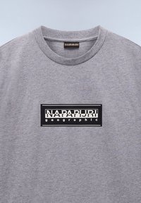 Camiseta de algodón gris con cuello redondo, que presenta un destacado logo rectangular en blanco y negro que dice "NAPAPURI geographic."