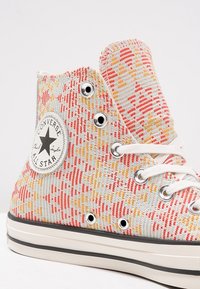 Hoge canvas sneakers met een kleurrijk geweven patroon in rood, oranje en blauw. Voorzien van witte veters en een ronde logopatch.