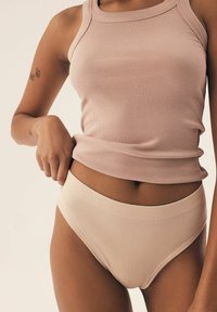 Helles rosa, geripptes Tanktop mit Rundhals-Ausschnitt, kombiniert mit cremfärbigen, gerippten Unterhosen mit nahtlosem Bündchen. Insgesamt glatte Textur.
