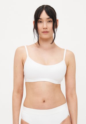 White seamless bralette with thin straps and a smooth texture. Features a minimalist design and elastic band at the bottom for support.
