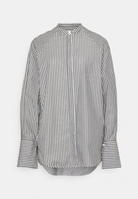 Chemise à manches longues à boutons, rayée verticalement en noir et blanc, avec un col montant et de larges poignets, sur un fond uni.