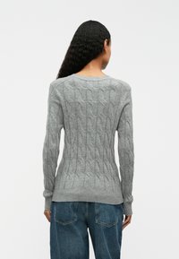 Grau gestrickter Pullover mit Kabelmuster, gerippten Bündchen und Saum. Leichter Stoff, Rundhalsausschnitt, taillierte Silhouette.