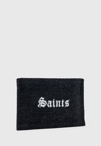 Črn pravokotni tekstilni žep z belim gotskim stilom napisom "Saints" centriranim na sprednji strani proti enotni podlagi.