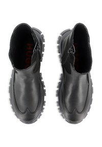 Botas tobilleras de cuero negro con un acabado suave, cierre de cremallera en el lateral y suela de goma resistente con dibujos pronunciados.