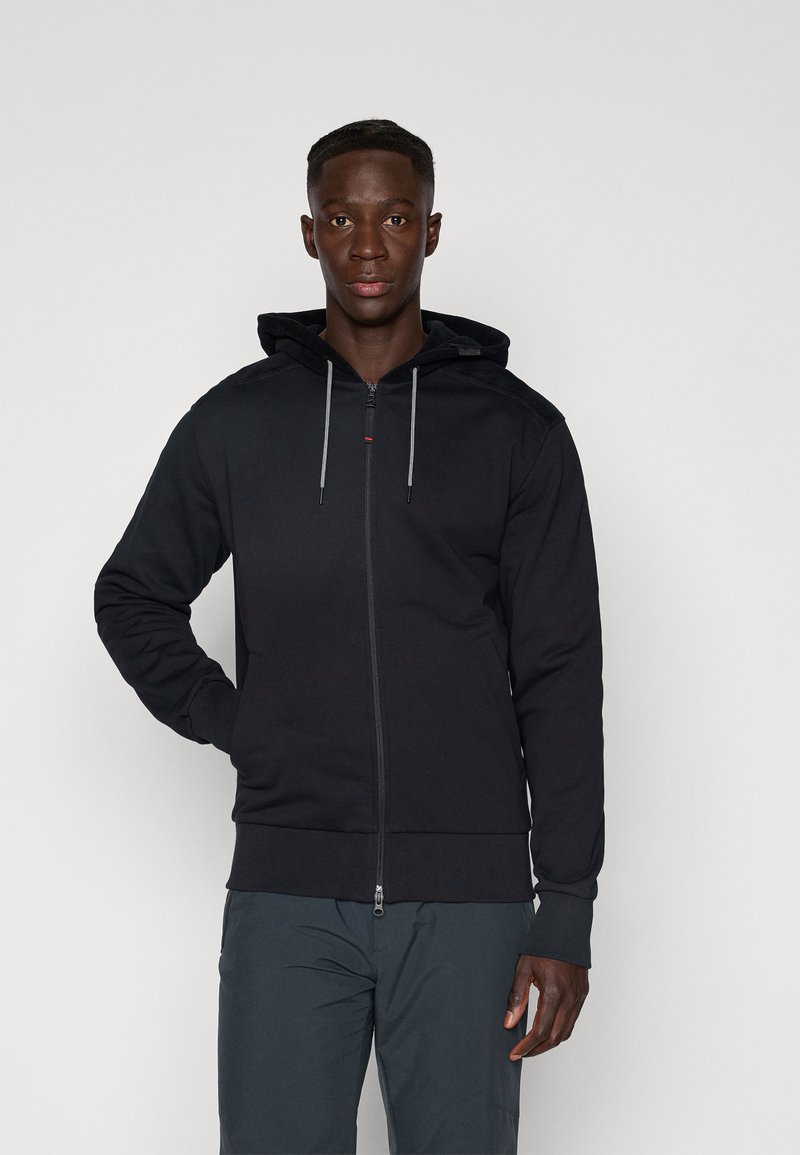 Hoodie noir zippé avec une fermeture éclair à l'avant, capuche à cordon de serrage et bords-côtes. Présente une texture unie et des détails de design subtils.