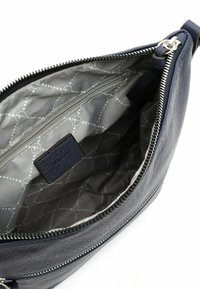 Interno della borsa in pelle blu navy, con una fodera grigia trapuntata caratterizzata da un motivo geometrico, tasca con zip e un'etichetta in pelle.