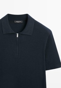 Granatowa, krótka, dzianinowa koszulka polo z prążkowaną fakturą i srebrnym suwakiem przy kołnierzu, oznaczona napisem "Massimo Dutti".
