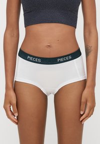 Bílé hipsterské spodní prádlo s tmavě zeleným elastickým pasem, na kterém je bíle uvedeno jméno značky "PIECES". Hladká tkanina a přiléhavý střih.