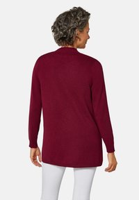 Cardigan long bordeaux avec une texture douce, encolure en V et poignets côtelés, présentant un ourlet droit et une longueur mi-thigh.