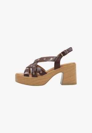 Sandale en cuir marron à brides avec œillets métalliques, boucle réglable, semelle intérieure rembourrée couleur fauve et talon bloc en bois massif.