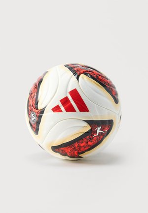 Biała piłka nożna Adidas z czerwono-czarnymi wzorami graficznymi i logo na jednolitym jasnym tle.