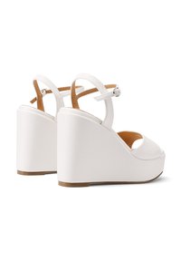 Comode scarpe con tacco a cuneo bianche, con punta aperta e cinturino alla caviglia, realizzate in materiale sintetico liscio, con una suola marrone chiaro e un design minimalista.