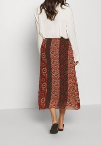 Maxi rok met een bloemen- en paisleypatroon in rood, bruin en crèmekleurige tinten; gemaakt van lichtgewicht stof, met een losse pasvorm voor comfort.