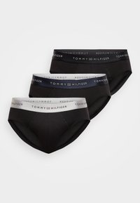 Τρία ζευγάρια ανδρικών σλιπ σε μαύρο και ναυτικό, με ελαστικές ζώνες μέσης που φέρουν λευκή επωνυμία "TOMMY HILFIGER". Λείος βαμβακερός ύφασμα.