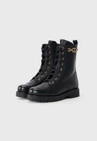 Black leather ankle boots with a textured finish, featuring gold eyelets, a lace-up design, a round toe, and a chunky black sole with a gold accent.