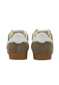 Bruna mockasn sneakers med en vit läderhäld och sidodetaljer. Rund tå och snörning. Gummisula med strukturerat mönster.