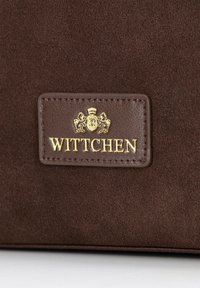 Bruine suede handtas met een gouden, geperst logo met leeuwen en kroon detail, verfraaid met bijpassende stiksels.