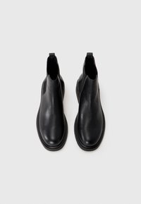 Black leather ankle boots with a smooth texture, rounded toe, elastic side panels, and a pull tab at the back. Flat rubber sole.